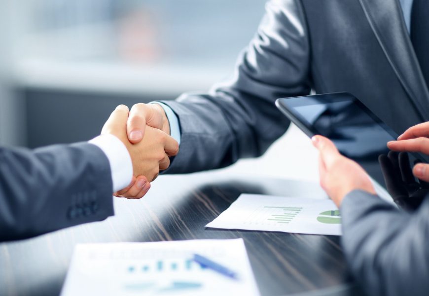 Two people in suits shaking hands regarding a financial or business agreement
