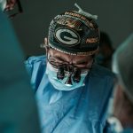 Doctor performing surgery wearing Green Bay Packers hat
